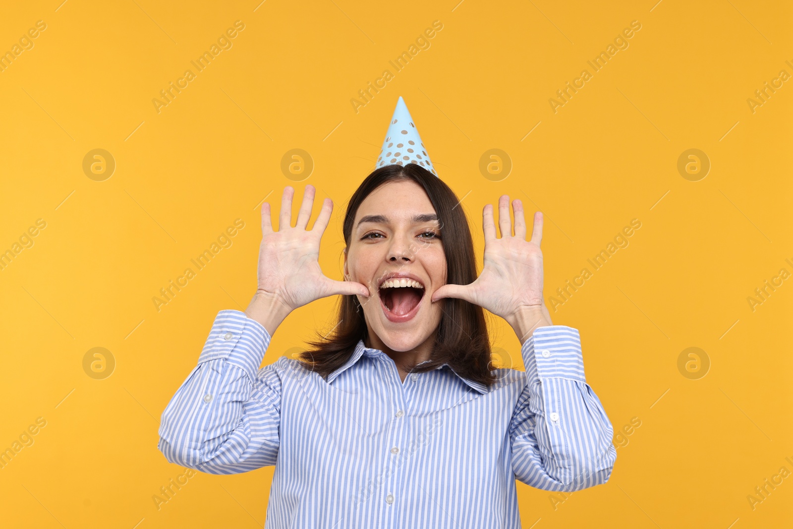 Photo of Happy young woman in party hat on yellow background