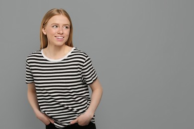 Photo of Portrait of beautiful young woman in striped t-shirt on grey background. Space for text