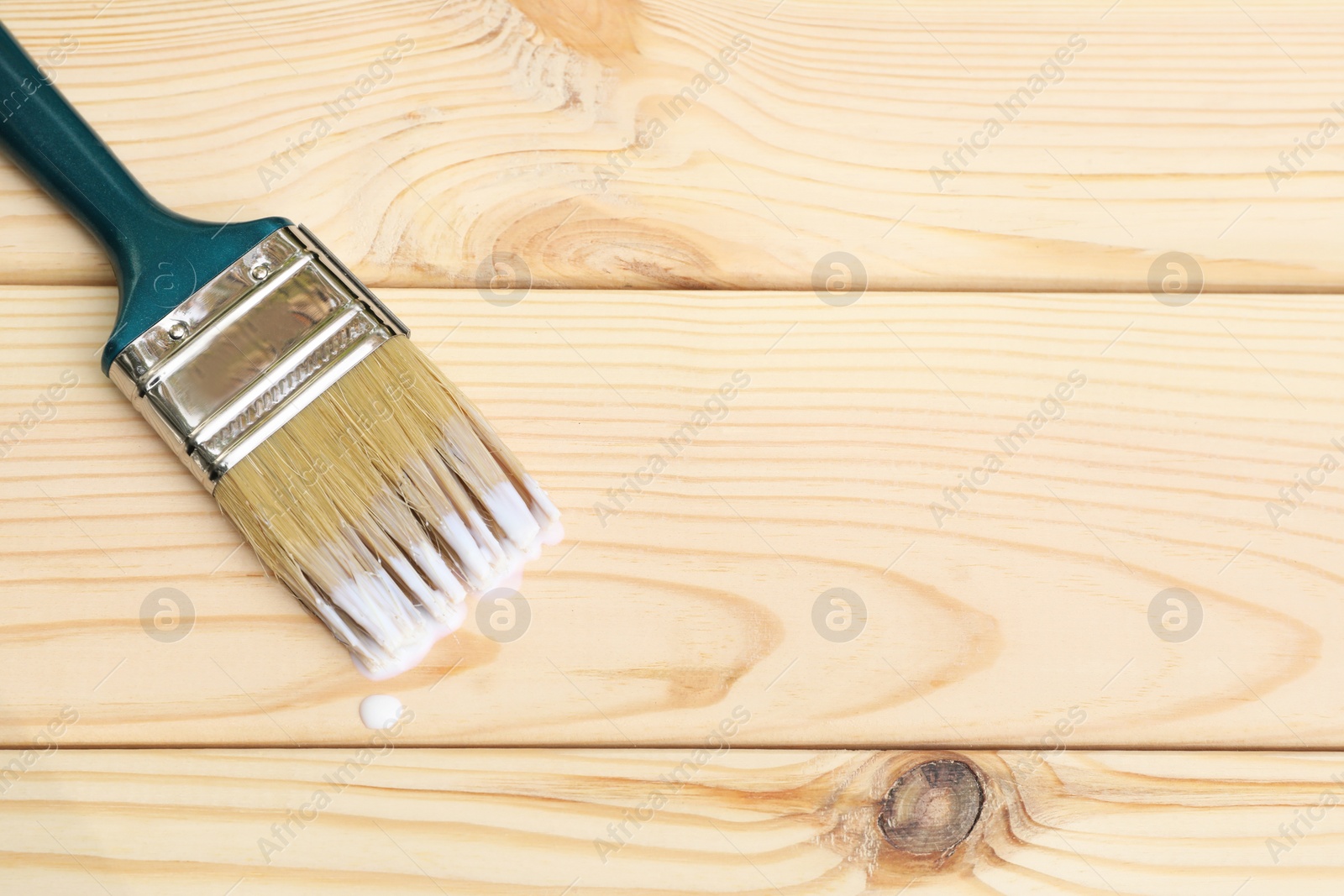 Photo of Brush with varnish on wooden surface, top view. Space for text