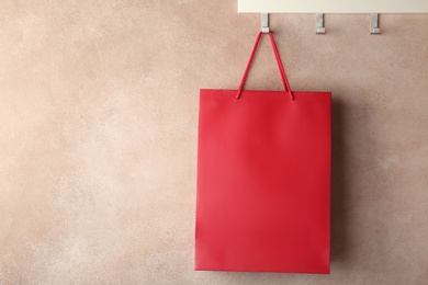 Photo of Rack with paper shopping bag on color wall. Mockup for design