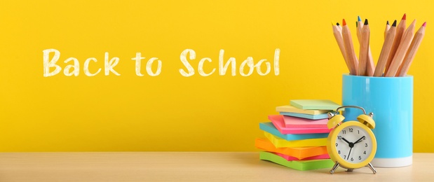 Text Back To School and different stationery on yellow background. Banner design 