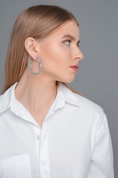 Photo of Beautiful young woman with elegant earrings on gray background