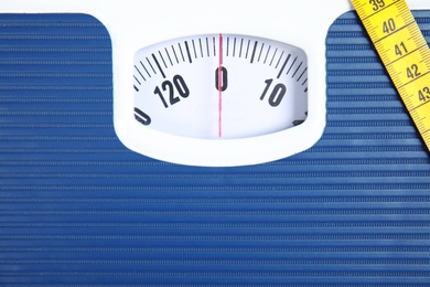 Photo of Scales with tape measure, closeup view. Diet and weight loss