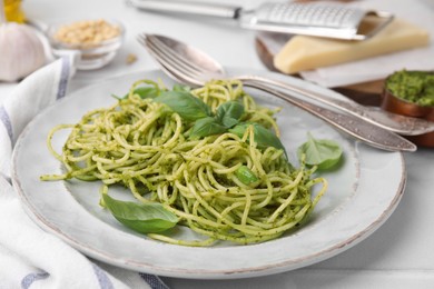 Photo of Delicious pasta with pesto sauce and basil on white table, closeup