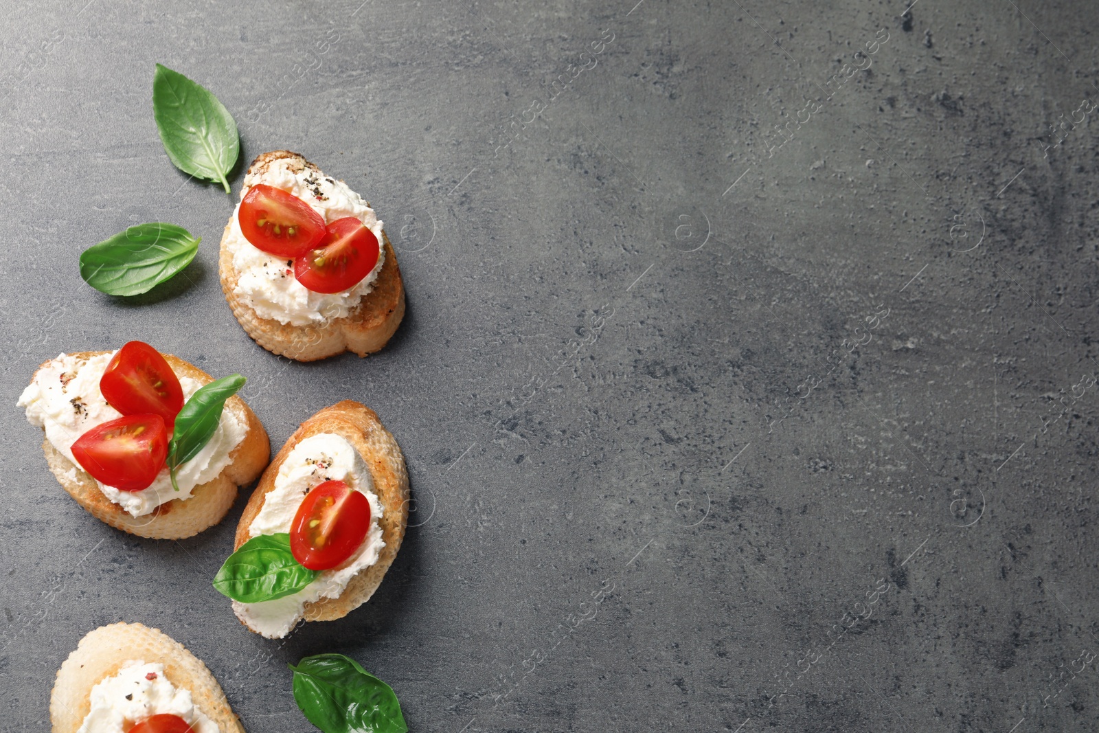 Photo of Pieces of baguette with tasty cream cheese and tomatoes on gray table, flat lay. Space for text