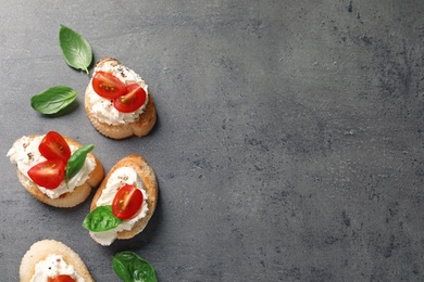 Photo of Pieces of baguette with tasty cream cheese and tomatoes on gray table, flat lay. Space for text