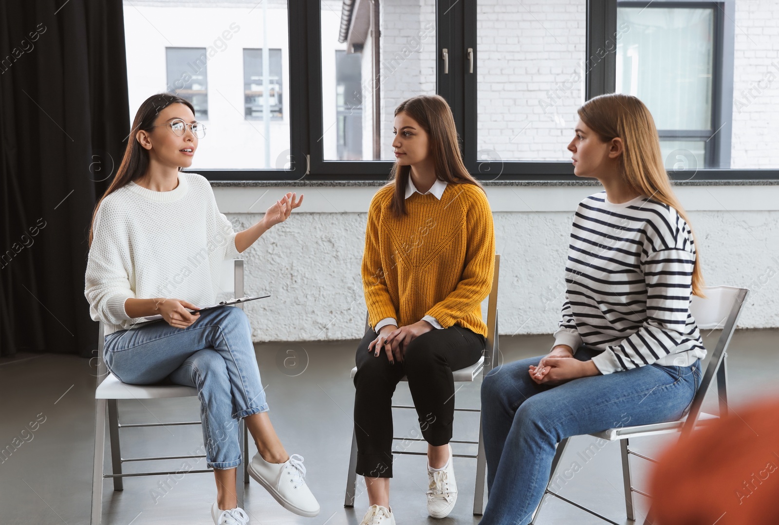 Photo of Psychotherapist working with patients in group therapy session indoors