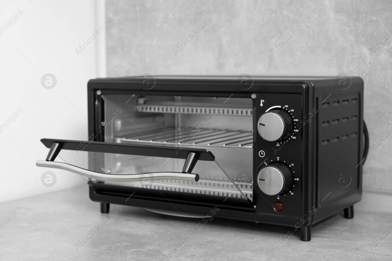 Photo of One electric oven on light grey table. Cooking appliance