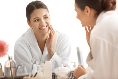 Photo of Beautiful young woman looking at herself in mirror indoors