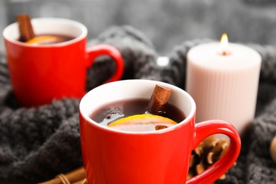 Photo of Cups of hot winter drink with scarf on window sill indoors, closeup