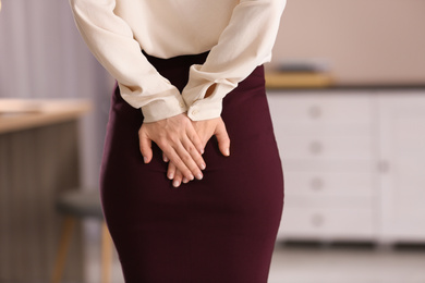 Photo of Young woman suffering from hemorrhoid in office, closeup