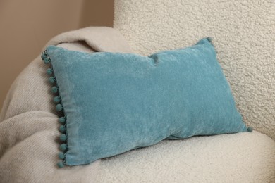 Photo of Soft blue pillow and blanket on armchair
