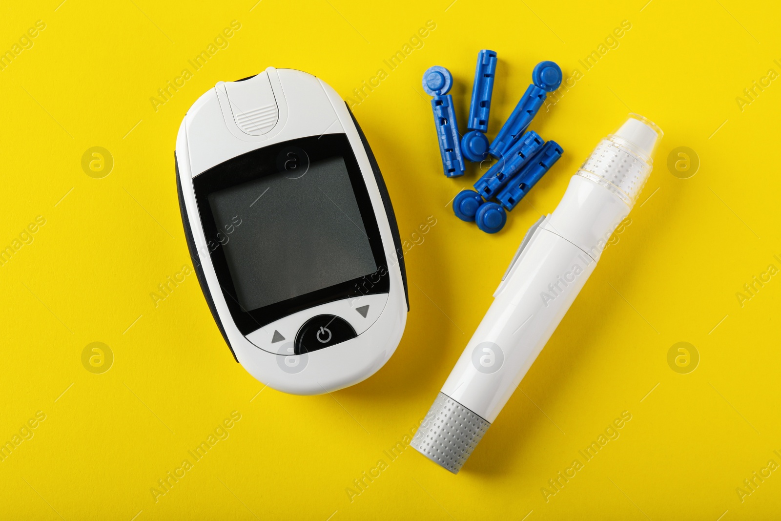 Photo of Digital glucometer, lancets and pen on yellow background, flat lay. Diabetes control