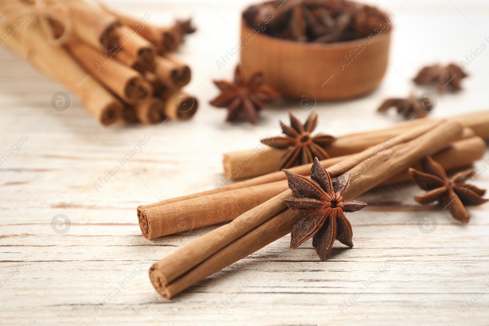 Photo of Aromatic cinnamon sticks and anise on white wooden table, closeup