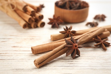 Photo of Aromatic cinnamon sticks and anise on white wooden table, closeup