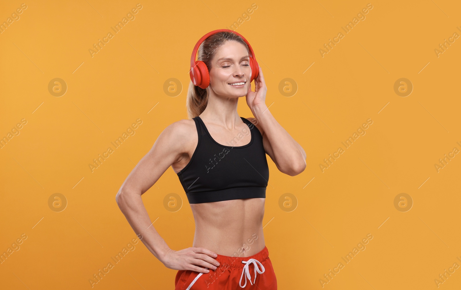 Photo of Sportswoman with red headphones on yellow background