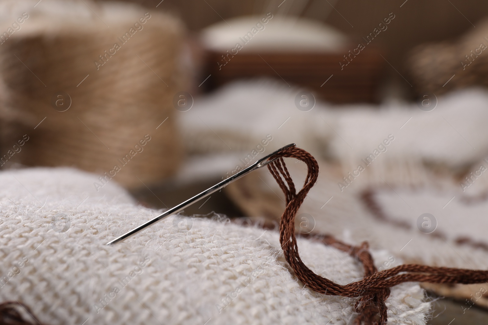 Photo of Heart made of burlap fabric with embroidery, needle and thread on table, closeup