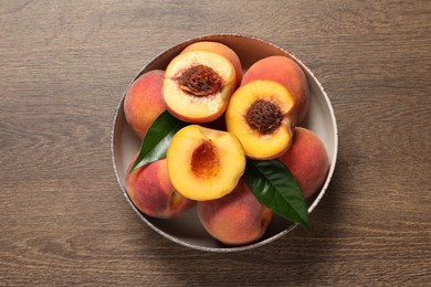 Photo of Plate with delicious juicy peaches and leaves on wooden table, top view