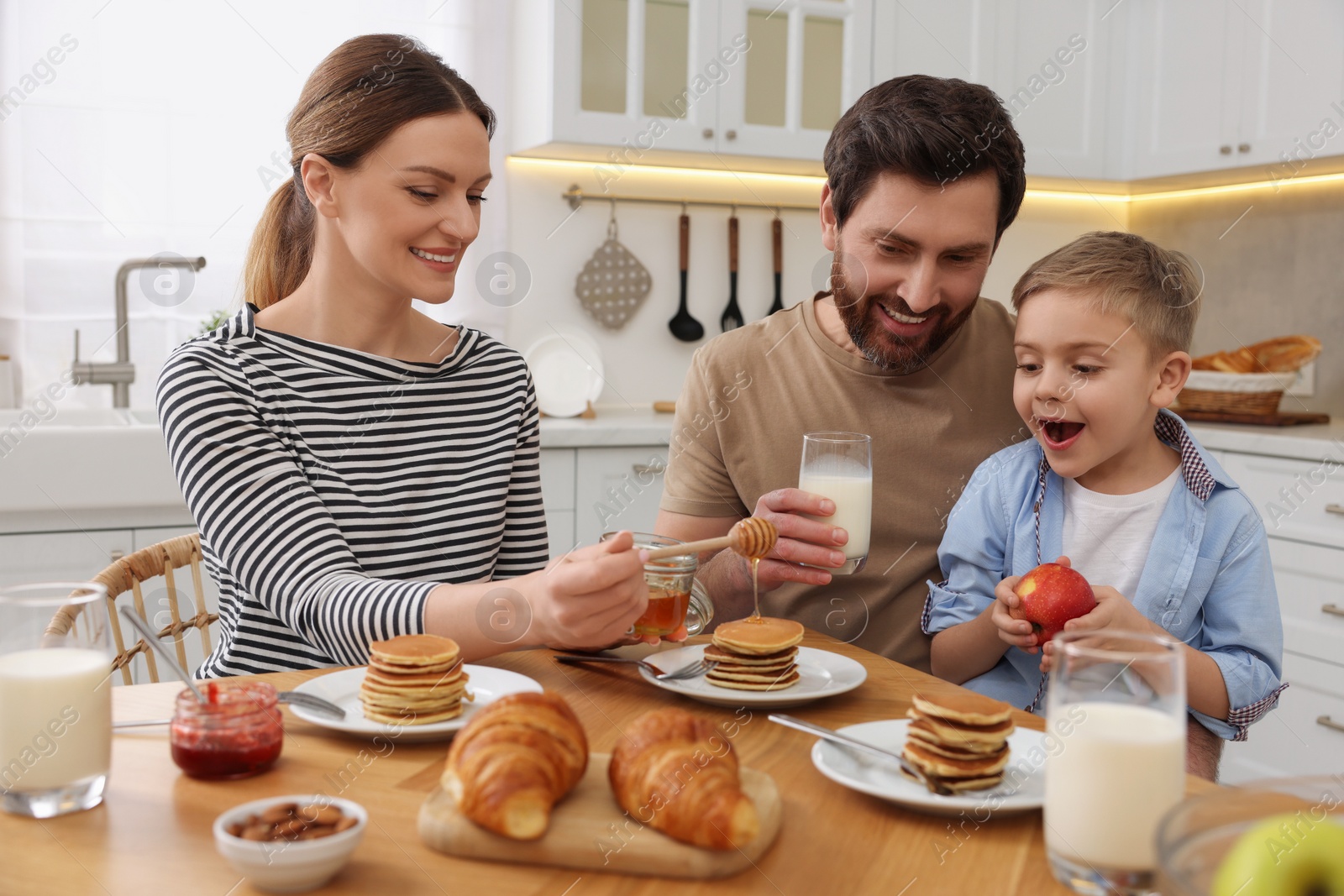 Photo of Happy family having breakfast at table in kitchen