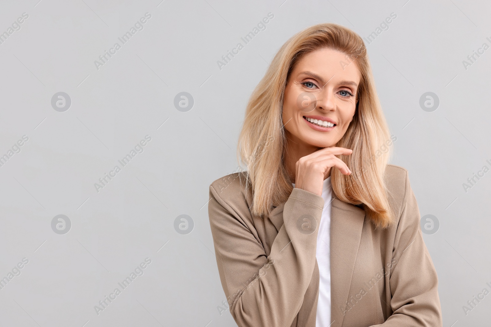 Photo of Portrait of smiling middle aged businesswoman on light grey background. Space for text