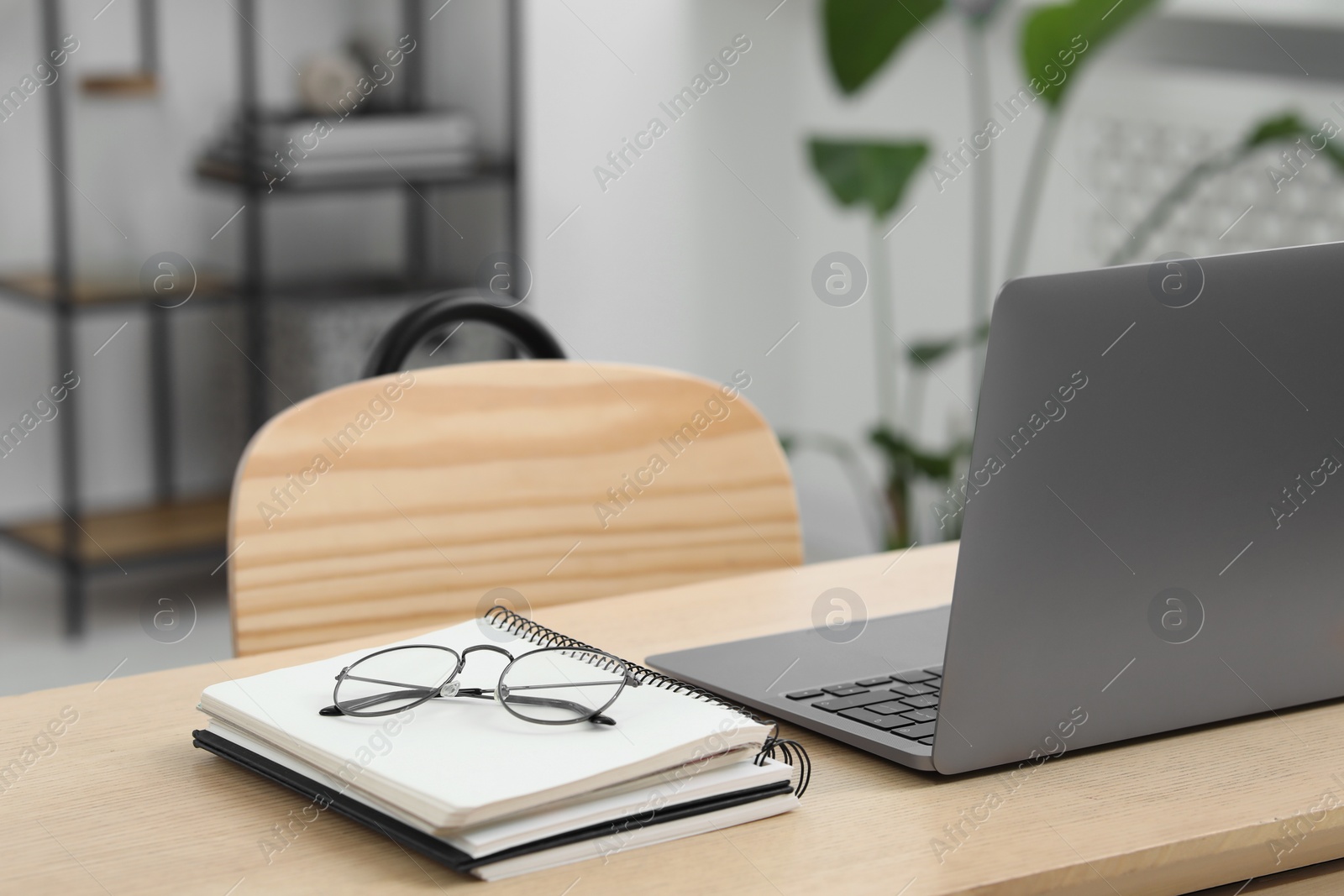 Photo of Home workspace. Laptop, glasses and stationery on wooden desk in room