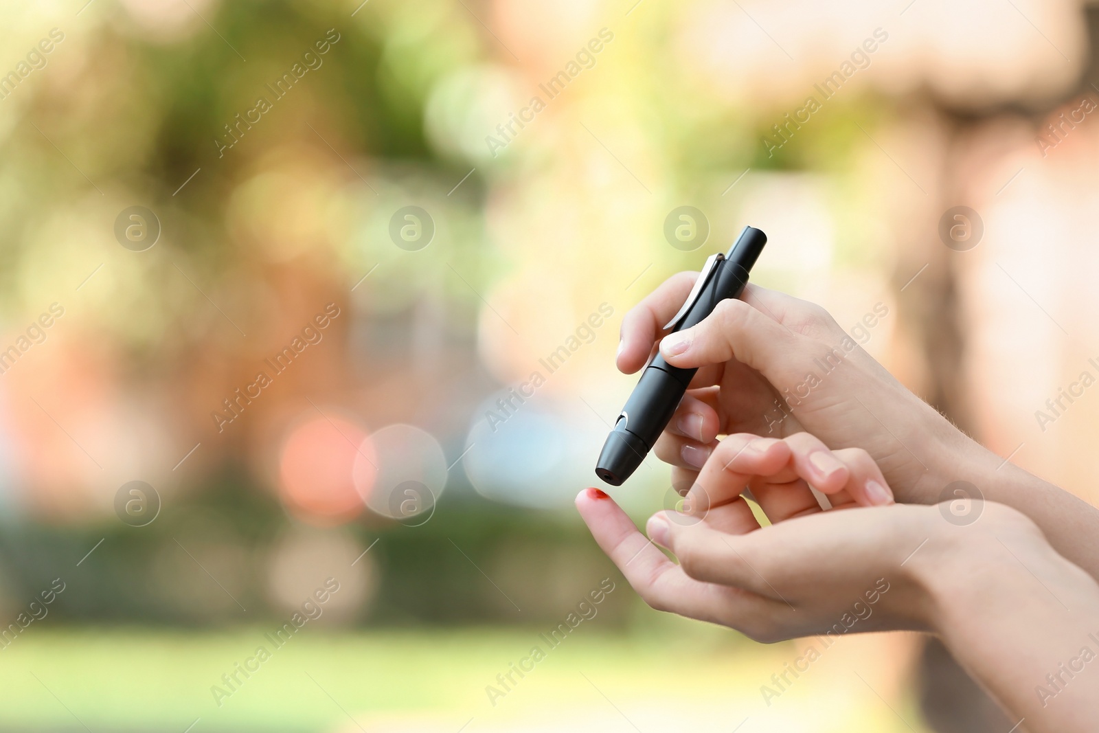 Photo of Woman using lancet pen on blurred background. Diabetes control