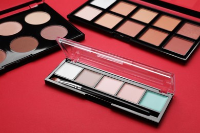 Colorful contouring palettes with brush on red background. Professional cosmetic product