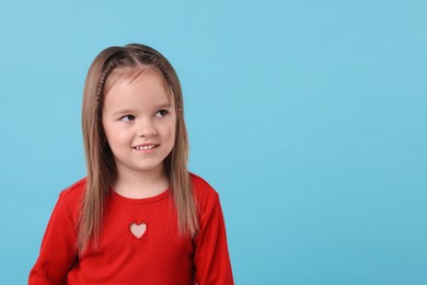 Portrait of happy little girl on light blue background, space for text