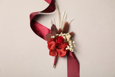 Stylish boutonniere and red ribbon on light grey background, top view