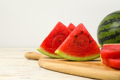 Photo of Slices of delicious ripe watermelon on white wooden table against light background