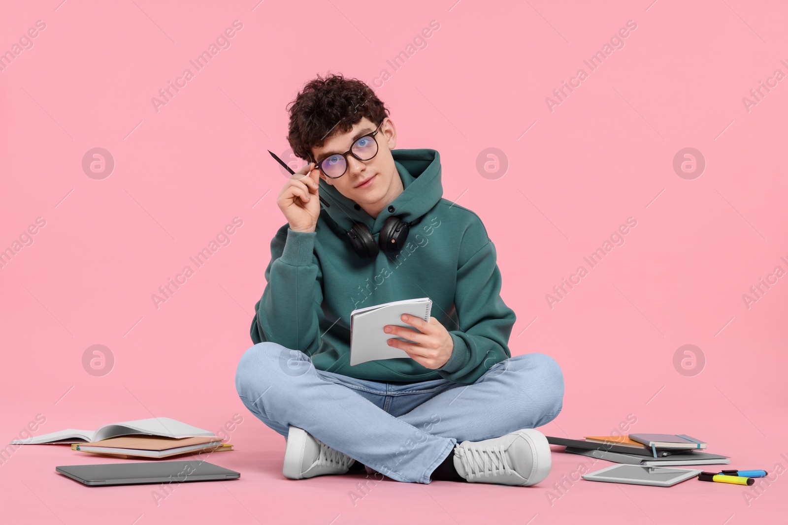 Photo of Portrait of student with notebook and stationery sitting on pink background