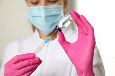 Doctor with vial and syringe in hospital, closeup. Vaccination day