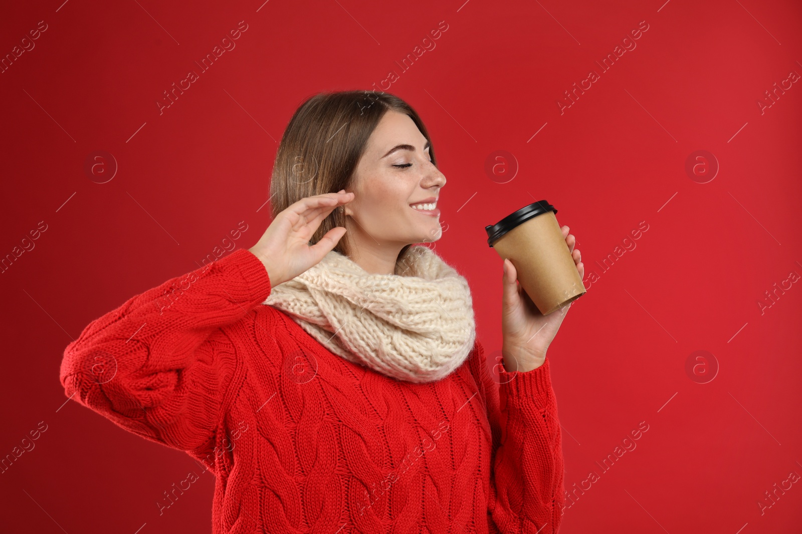 Photo of Happy beautiful woman with paper cup of mulled wine on red background