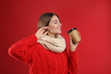 Happy beautiful woman with paper cup of mulled wine on red background