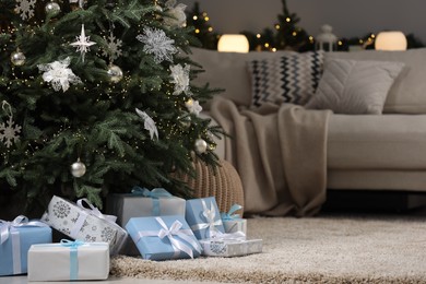 Photo of Many different gifts under Christmas tree on carpet indoors, space for text
