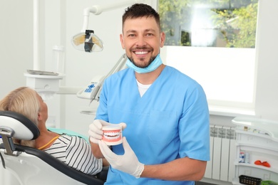 Photo of Professional dentist holding jaws model in clinic