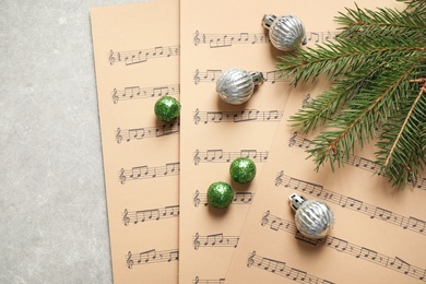 Photo of Christmas decorations and music sheets on grey stone table, flat lay