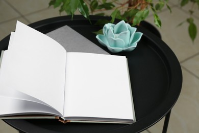 Open blank book and flower shaped figure on black table indoors, closeup