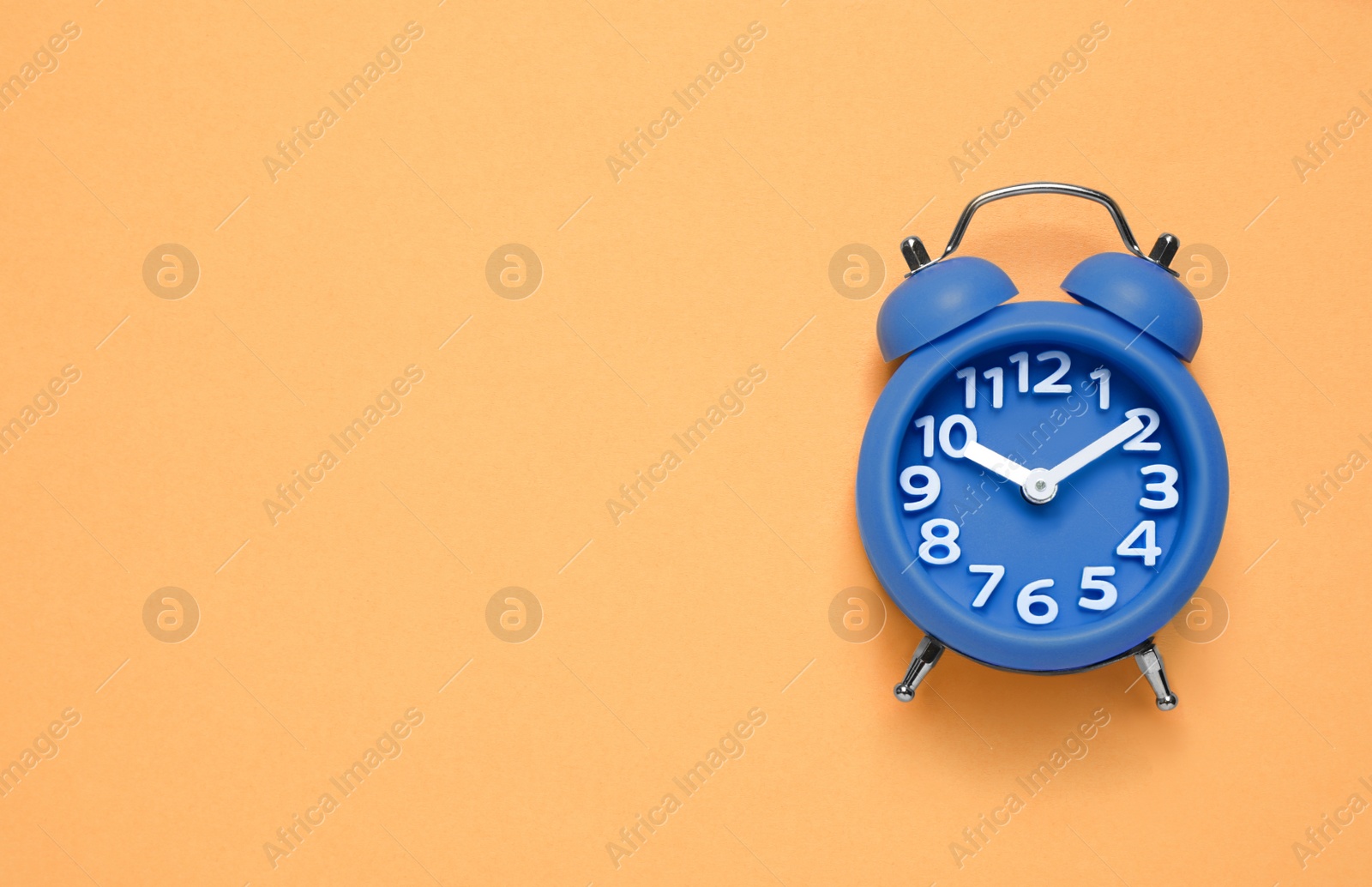 Photo of Alarm clock on orange background, top view with space for text. Color of the year 2020 (Classic blue)