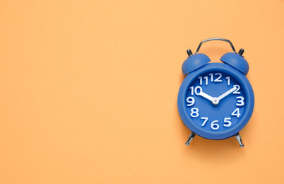 Alarm clock on orange background, top view with space for text. Color of the year 2020 (Classic blue)