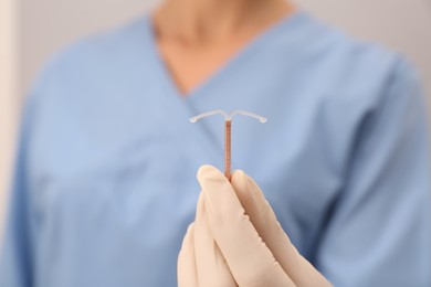 Photo of Doctor holding T-shaped intrauterine birth control device, closeup