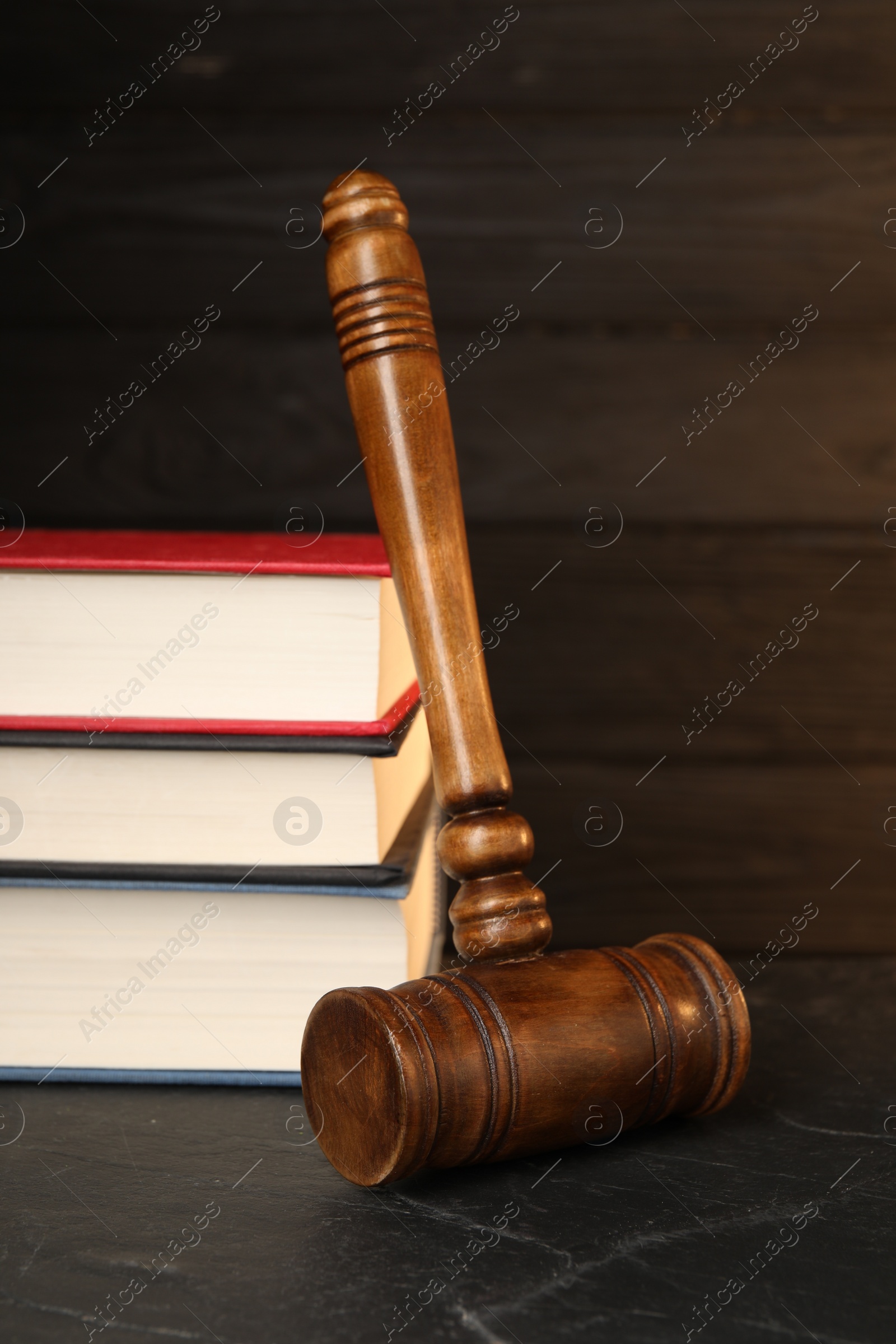 Photo of Wooden gavel and stack of books on dark textured table