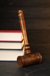 Photo of Wooden gavel and stack of books on dark textured table