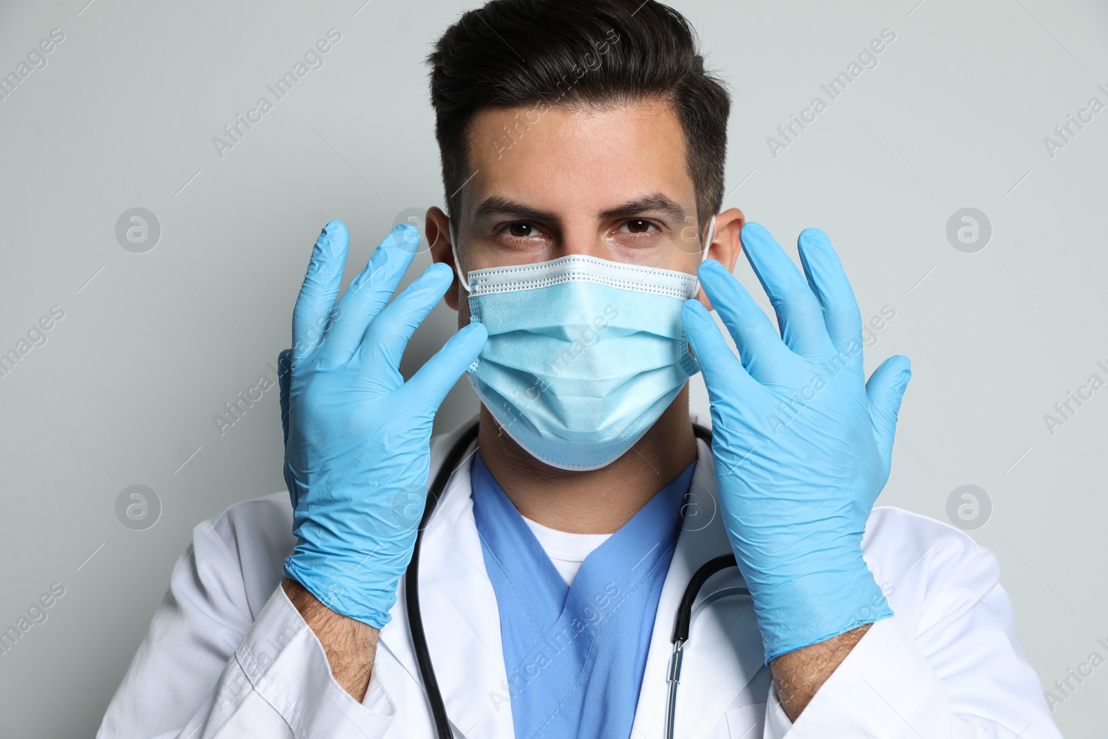 Photo of Doctor in protective mask and medical gloves against light grey background