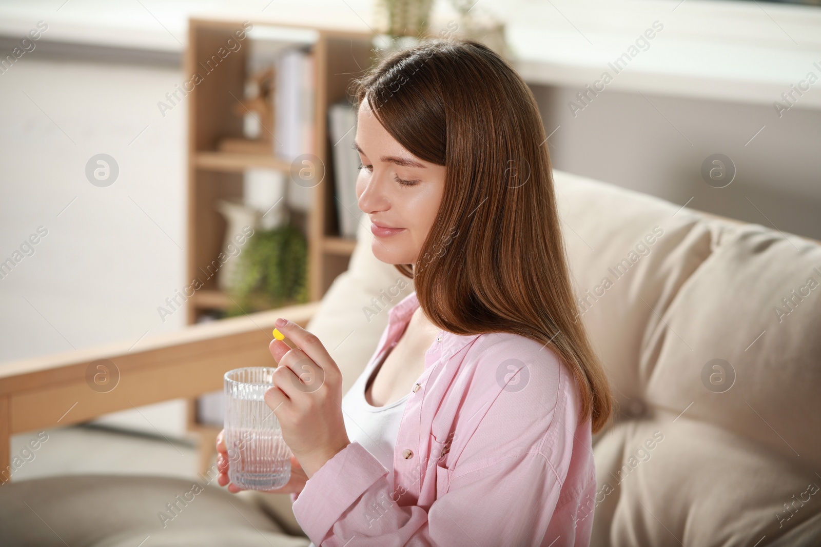 Photo of Beautiful pregnant woman holding pill and glass of water at home