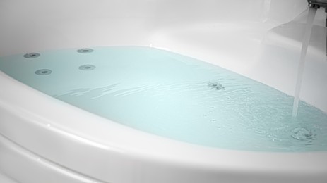 Photo of Water running into hot tub in bathroom, closeup