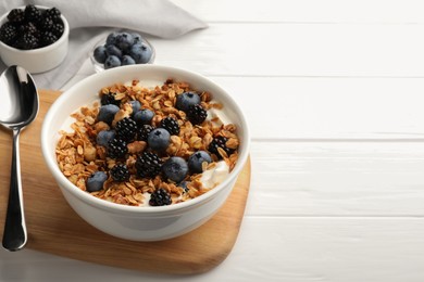 Bowl of healthy muesli served with berries on white wooden table, space for text