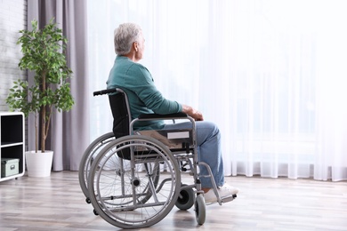 Photo of Senior man sitting in wheelchair near window at home