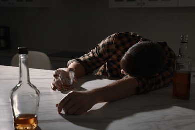 Photo of Addicted man with alcoholic drink sleeping at table in kitchen