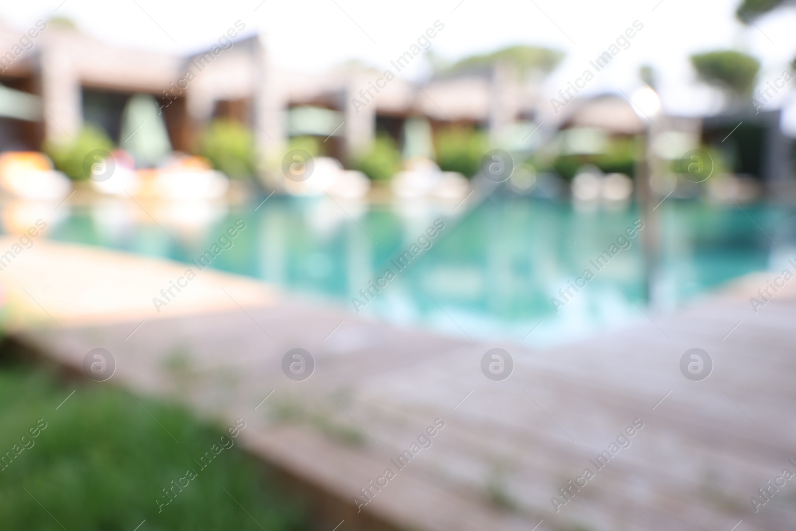 Photo of Outdoor swimming pool with wooden deck, blurred view. Luxury resort